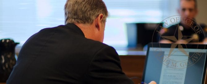 Man in black suit using a tablet during a legal consultation at Greaves Law office.