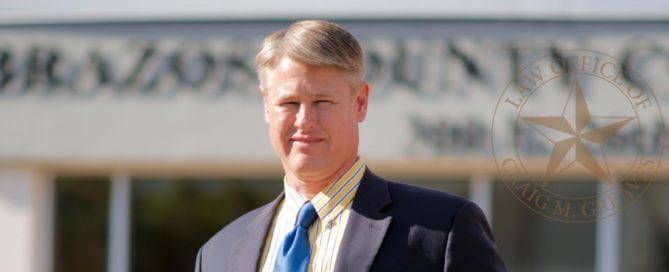 A man in a suit standing outdoors in front of a blurred law office sign.