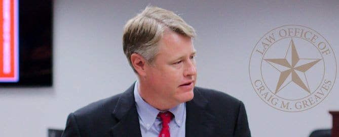 Man in suit and tie speaking in a law office with Craig M. Greaves logo in background.