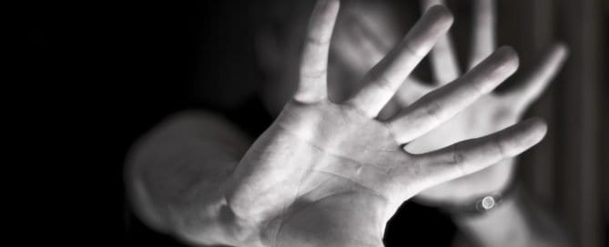 Person holding up hand in a stop gesture, face obscured.