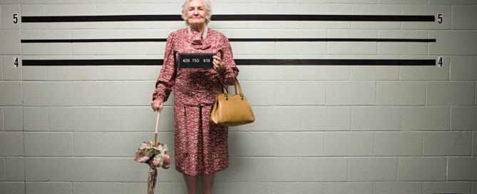 Elderly woman in pink dress standing in front of a height measurement wall.