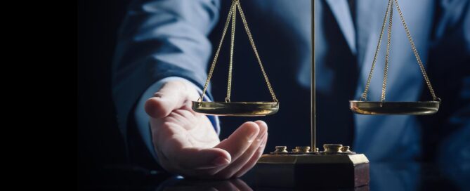 Close-up of a person in a suit holding a balance scale, symbolizing justice.